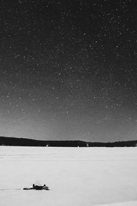 Person lying down on snow covered landscape against star field