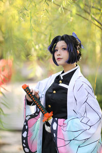 Portrait of young woman standing against trees