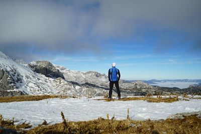 Rear view of man standing on mountain against sky