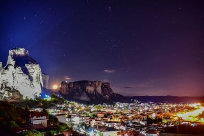 Illuminated buildings in town against sky at night