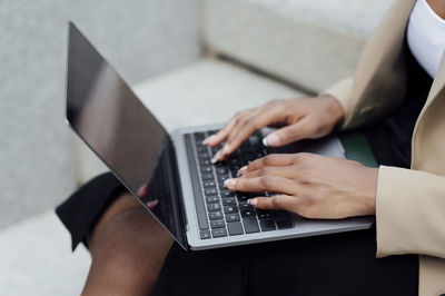 Businesswoman working on laptop sitting on bench