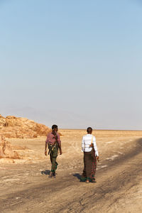 Rear view of men walking on desert