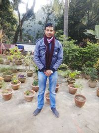 Portrait of young man standing against plants