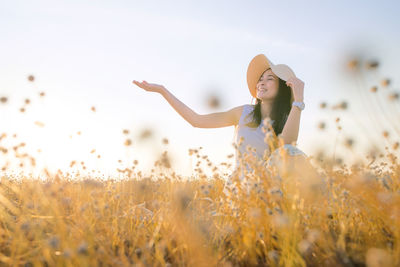 Woman standing on field against sky during sunset