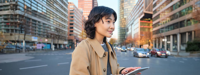 Young woman looking away while standing in city