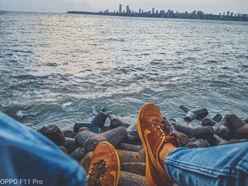 Low section of people relaxing on rock by sea