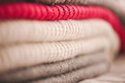 Stack of bright color knitted clothes on shelf in store close up. warm and cozy colorful sweaters. 