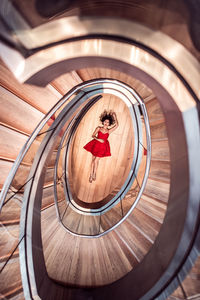 Directly above shot of woman lying on floor amidst spiral staircase