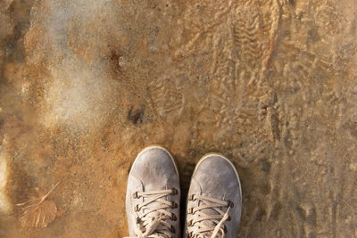 Feet snow puddles. light brown boots top view. neutral color scheme. natural earthy 