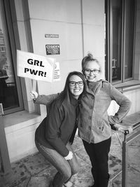 Portrait of smiling sisters standing against wall