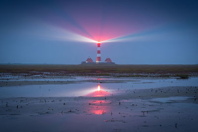 View of lighthouse at seaside during sunset