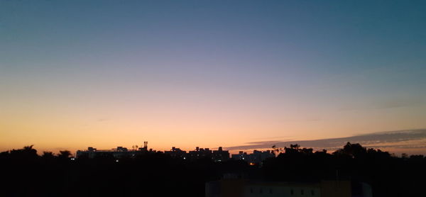 Silhouette buildings against clear sky at sunset