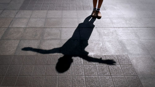 Low section of man walking on footpath with shadow