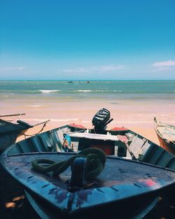 Boats moored on beach against blue sky