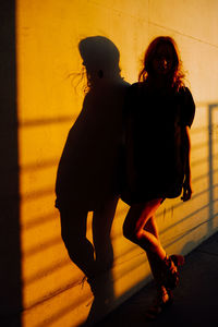 Portrait of silhouette women standing by wall