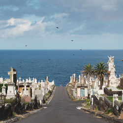 Road amidst waverley cemetery leading towards sea against sky