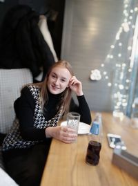 Portrait of a smiling young woman sitting on table