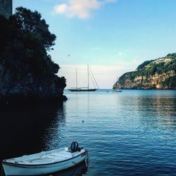 Sailboats moored in sea against sky