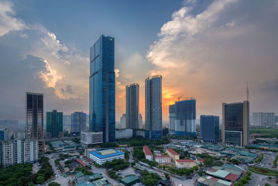 Modern buildings in city against sky during sunset