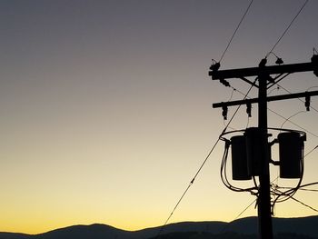 Low angle view of ski lift against sky during sunset