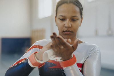 Teenage girl applying chalk powder on hands at gym