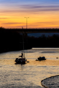 Silhouette sailboat sailing on sea against sky during sunset