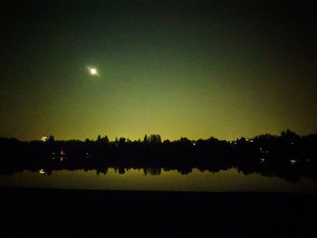 Silhouette trees on field against sky at night