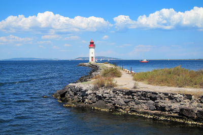 Lighthouse by sea against sky