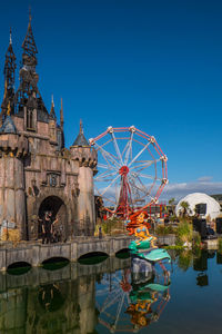 Ferris wheel in city against clear blue sky