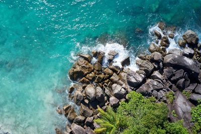 Drone field of view of turquoise water and beautiful rocks meeting sea mahe, seychelles.