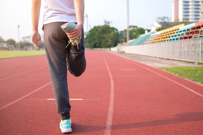 Low section of woman stretching on running track