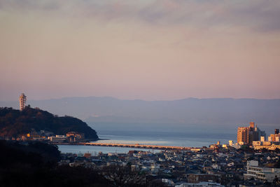 Town by sea against sky during sunset