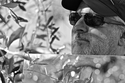 Close-up of man holding mirror while standing by plants