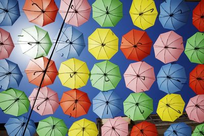 Low angle view of colorful umbrellas hanging against sky during sunny day
