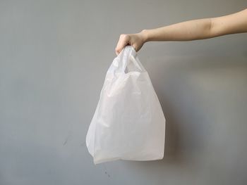 Close-up of hand holding paper against white background