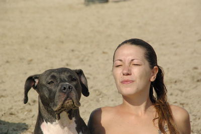 Close-up of woman with eyes closed by dog at beach during sunny day