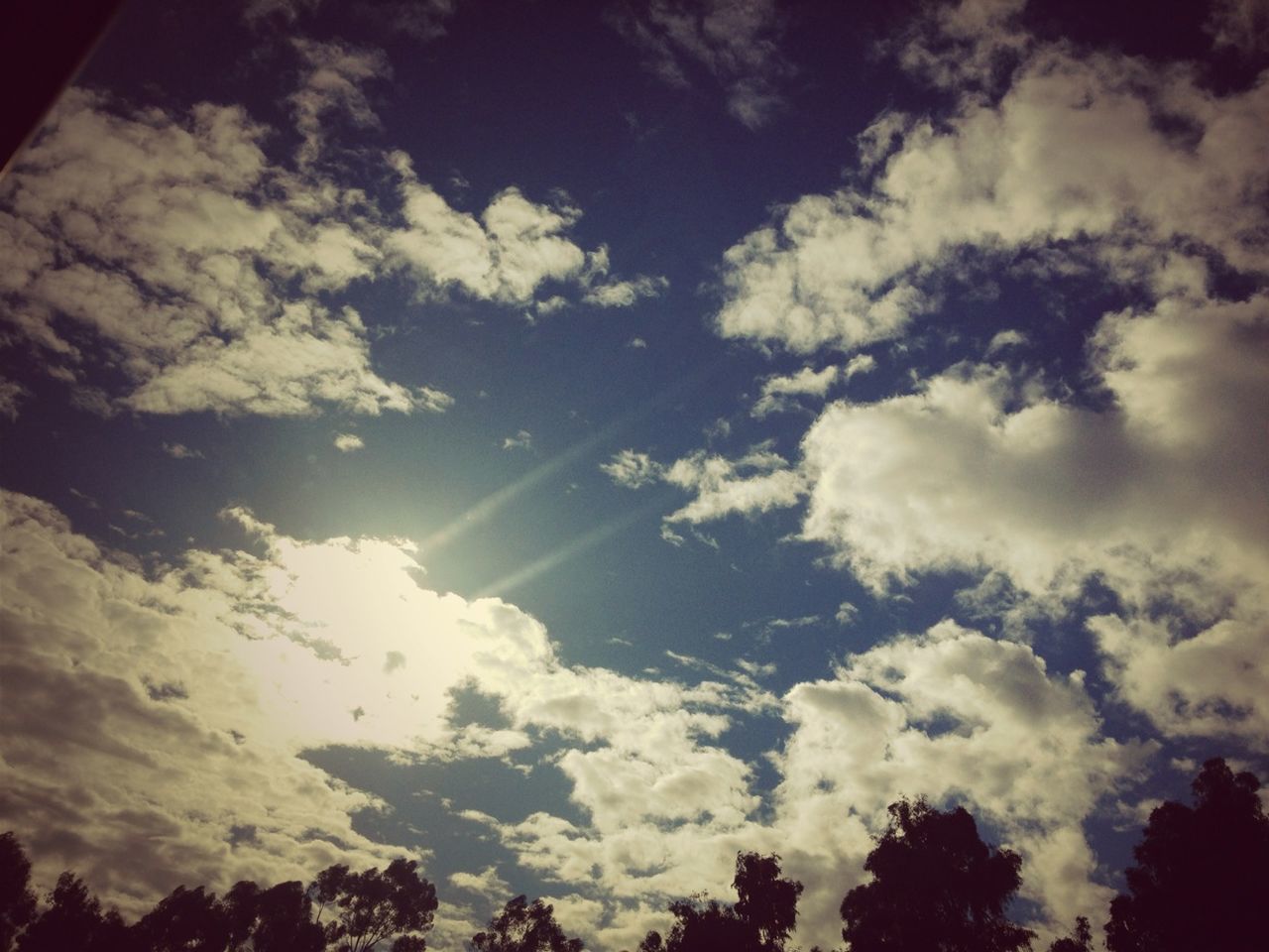 low angle view, sky, cloud - sky, beauty in nature, tranquility, scenics, silhouette, tranquil scene, nature, cloudy, tree, cloud, cloudscape, idyllic, sunlight, outdoors, no people, sunbeam, backgrounds, day