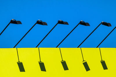 Low angle view of street lights against clear blue sky