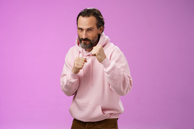 Determined man making combat pose against purple background