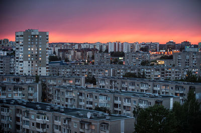 Illuminated buildings in city against sky at sunset