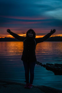 Full length of silhouette woman standing at beach during sunset