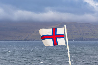 Flag on sea against sky