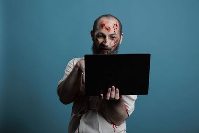 Portrait of young man using digital tablet against black background