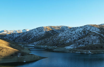 Scenic view of lake and mountains against clear blue sky