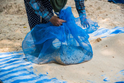 Low section of person cleaning sand at beach