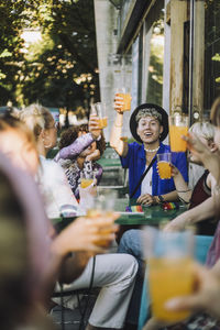 Happy young man enjoying drink while sitting with friends