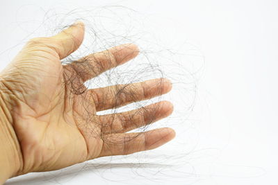Cropped hand holding hair against white background