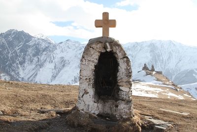 Cross on mountain against sky during winter