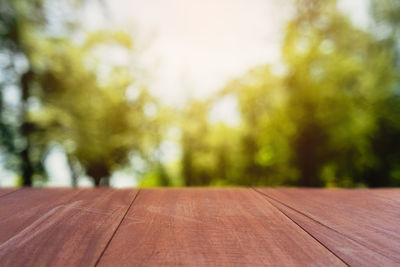 Surface level of wooden table against trees