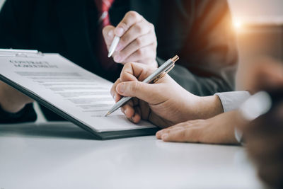 Close-up of man holding paper with hand on table